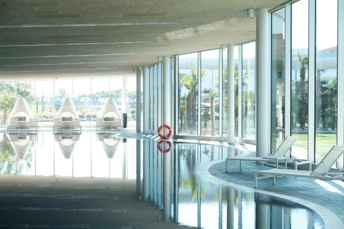a lobby with chairs and a pool in a building at Mjus Resort & Thermal Park in Körmend