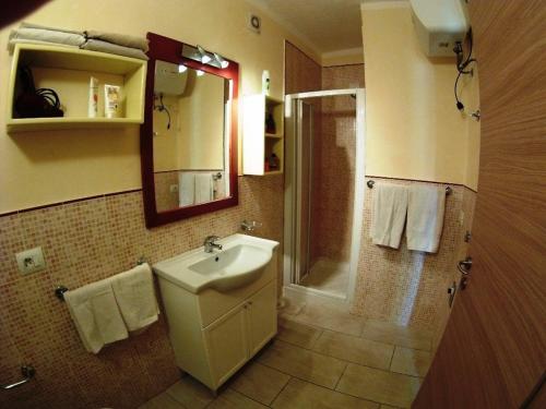 a bathroom with a sink and a shower with a mirror at Djasal Moradias Apartment in Santa Maria