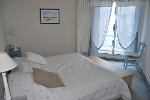une chambre avec un lit blanc et une fenêtre dans l'établissement Appartement La Baule Plage, à La Baule
