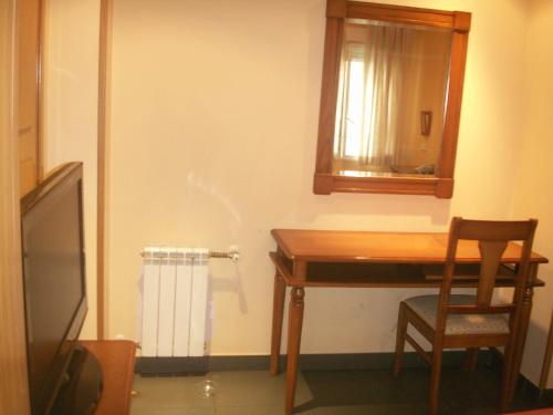 Zimmer mit einem Schreibtisch, einem Tisch und einem Spiegel in der Unterkunft Hostal La Nava in Madrid