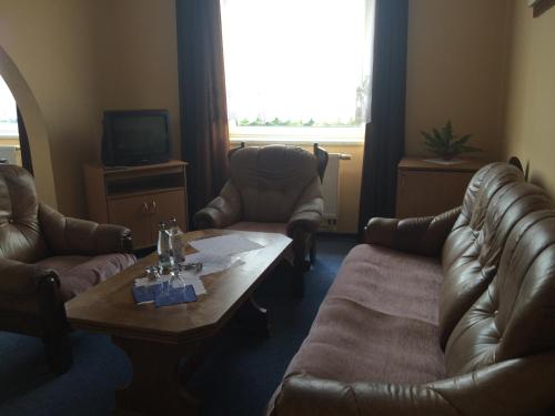 a living room with couches and a table and a tv at Hotel Belvedere Příbram in Příbram