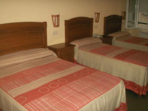 a hotel room with three beds in a room at Hostal La Nava in Madrid