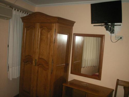 a bedroom with a wooden cabinet and a mirror at Hostal La Nava in Madrid