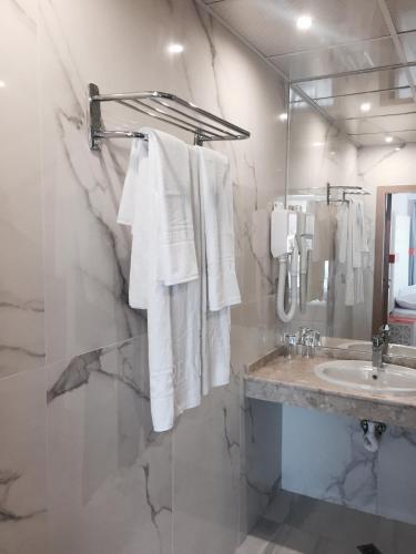 a white bathroom with a sink and a mirror at Hotel Perla Beach Luxury - All Inclusive & Free Beach Access in Primorsko