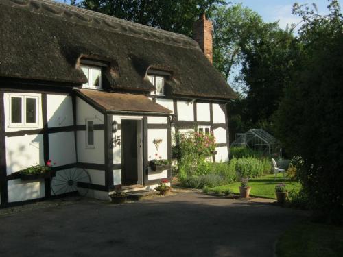 Ce cottage blanc est doté d'un toit de chaume. dans l'établissement The Moats - Ledbury, à Ledbury