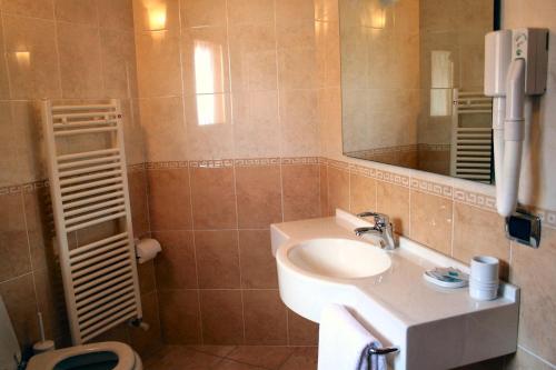 a bathroom with a sink and a mirror and a toilet at Hotel Sole in Castione della Presolana