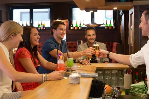 a group of people sitting at a bar with drinks at Hotel Wagrainerhof in Wagrain