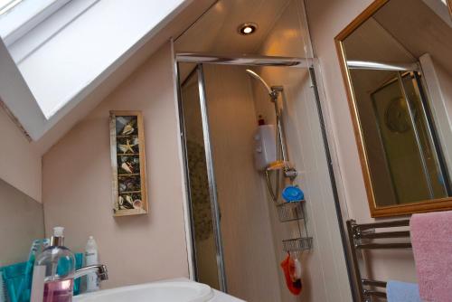 uma casa de banho com um chuveiro, um WC e um lavatório. em Room by the Beach em Aird Tong