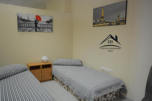 a room with two beds and a sign on the wall at Center Apartman - Paks in Paks