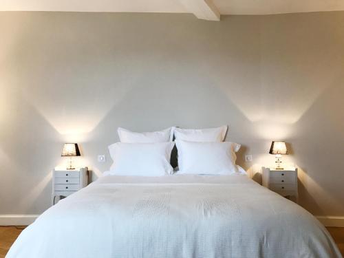 a bedroom with a large white bed with two lamps at Chambres d'hôtes Vers la Croix in Leynes