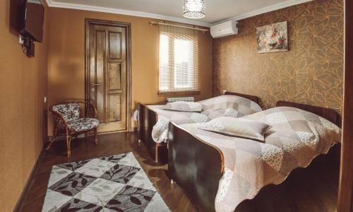 - une chambre avec 2 lits, une chaise et une télévision dans l'établissement Casa de Khasia, à Zugdidi