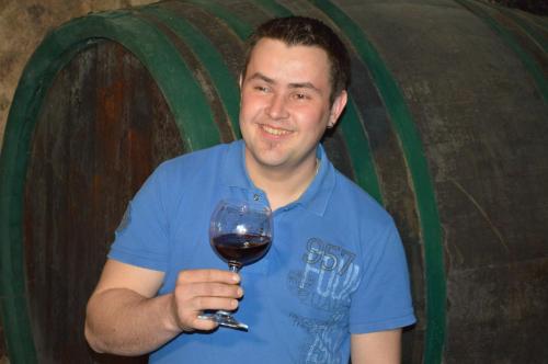 a man holding a glass of wine in front of a barrel at Andreashof Mörbisch in Mörbisch am See