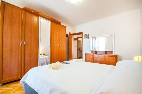a bedroom with a large white bed and wooden cabinets at La Mia Apartment in Dubrovnik