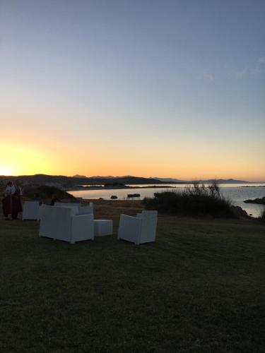 a group of white chairs sitting on the beach at sunset at Camera vista mare, ingresso indipendente in" Villa VìVì" in Siniscola