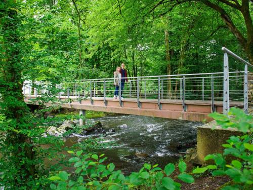 two people standing on a bridge over a river at Domaine de Blangy in Hirson