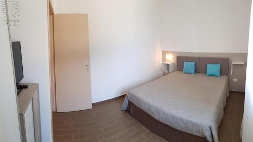 a bedroom with a bed with blue pillows and a television at Case Vacanza Marzano in Monopoli