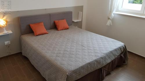 a bedroom with a bed with two orange pillows on it at Case Vacanza Marzano in Monopoli