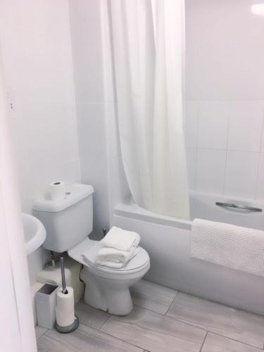 ロンドンにあるCharimore Executive Apartmentのトイレと浴槽を備えた白いバスルーム