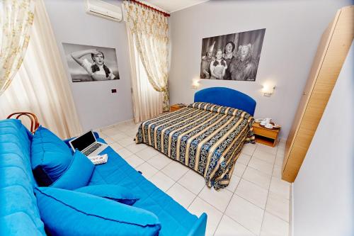 a living room with a blue couch and a bed at Hotel Ospite Inatteso in Montalto di Castro