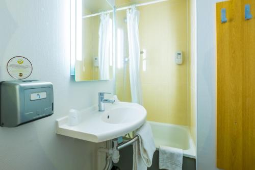 Baño blanco con lavabo y espejo en B&B HOTEL Valence Nord, en Bourg-lès-Valence