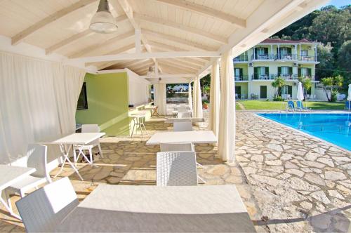 patio ze stołami i krzesłami przy basenie w obiekcie Vliho Bay Suites & Apartments w mieście Yénion