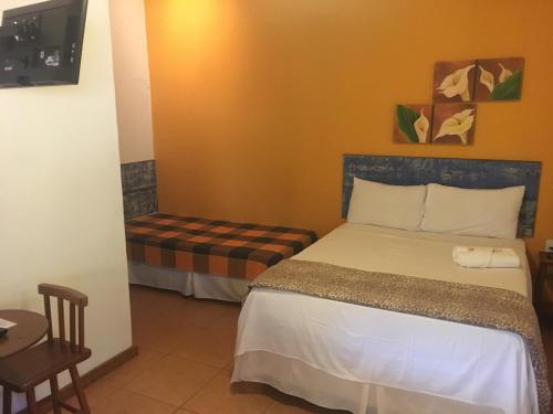 a small bedroom with a bed and a chair at Pousada Pepalantus in Serra do Cipo