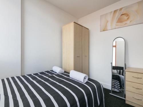 een slaapkamer met een zwart-wit gestreept bed en een dressoir bij Contractor Apartments in Manchester