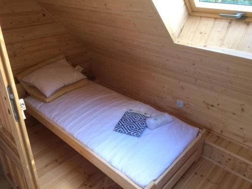 a small bed in a wooden cabin with a window at Domek w Sercu Mazur in Ryn