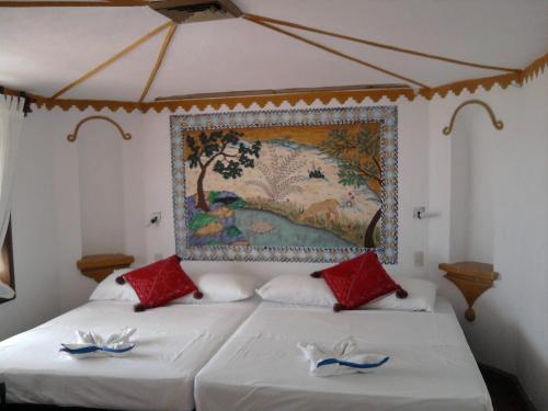 a bedroom with two beds with a painting on the wall at Hotel Paraiso Escondido in Puerto Escondido