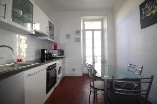 une cuisine avec une table et un évier et une table et des chaises dans l'établissement AGENCIA apartement 3 PIECES RUE D'ANTIBES, à Cannes
