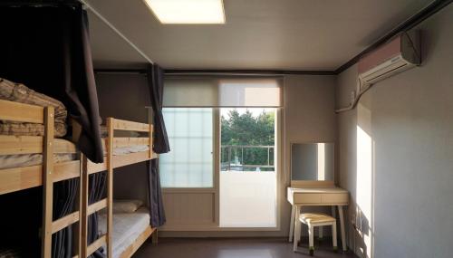 a dorm room with bunk beds and a window at Blue Door Hostel Guesthouse in Sokcho