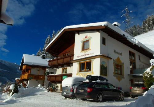 a building with cars parked outside of it in the snow at Pension Alpengruss in Gerlos