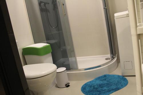 a bathroom with a toilet and a shower with a blue rug at 3-Studio in Poznań