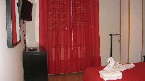 a room with a red curtain and a bed and a television at Caminito ARG in La Bañeza