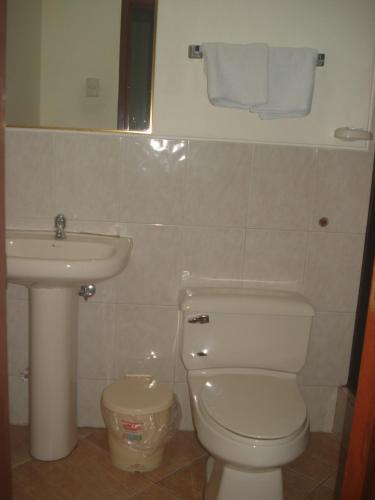 a bathroom with a white toilet and a sink at Hotel Murcia in Guayaquil
