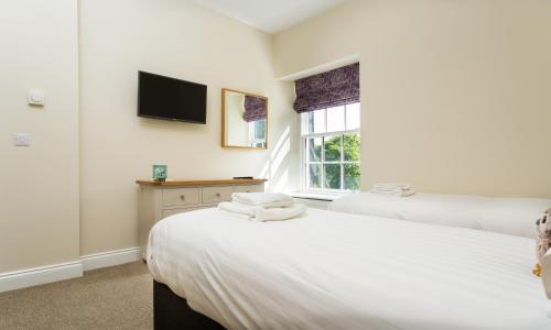 two beds in a bedroom with a tv on the wall at Waterfoot Park in Pooley Bridge