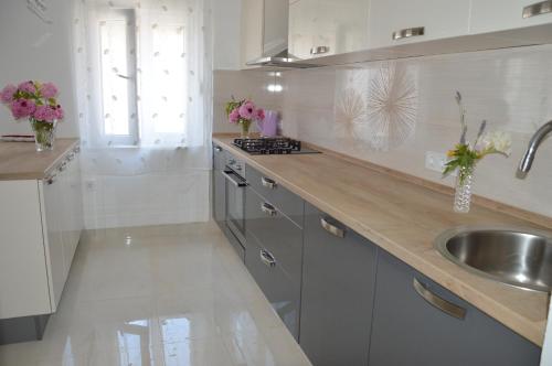a kitchen with a sink and a counter with flowers at Apartments Babic in Podstrana