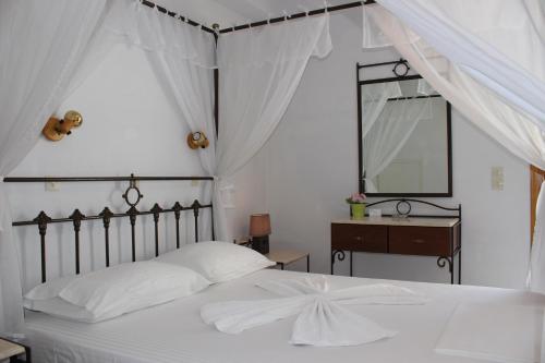 um quarto com uma cama branca, uma cómoda e um espelho. em Olympion Apartments em Stafylos