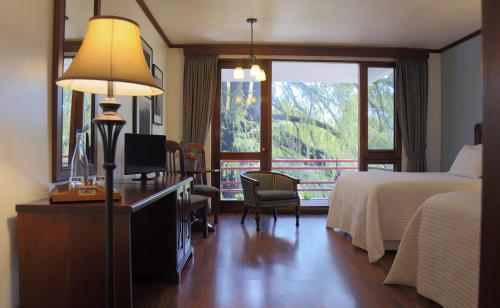 a hotel room with a bed and a desk with a lamp at Hotel Residencia del Sol in Guatemala