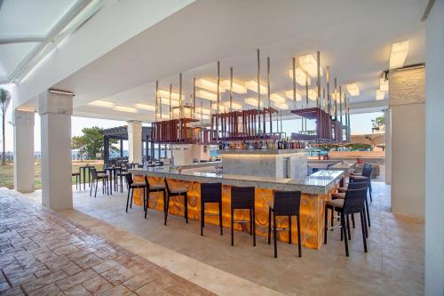 a restaurant with a bar with chairs and a bar counter at Grand Lido Negril Au-Naturel, An Autograph Collection All-Inclusive Resort - Adults Only in Negril