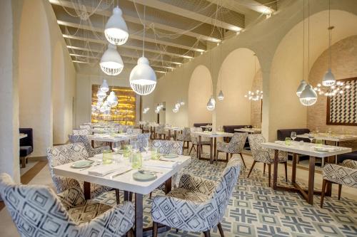 a restaurant with white tables and chairs and chandeliers at Grand Lido Negril Au-Naturel, An Autograph Collection All-Inclusive Resort - Adults Only in Negril