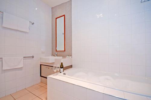 a white bathroom with a tub and a sink at Beacon Point Ocean View Villas in Apollo Bay