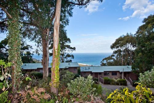 a building with trees and the ocean in the background at Beacon Point Ocean View Villas in Apollo Bay