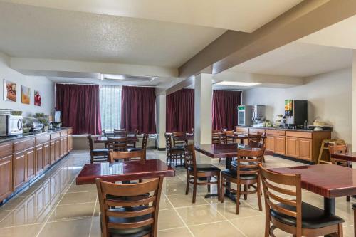 a restaurant with wooden tables and chairs and a kitchen at Days Inn by Wyndham Hartsfield Jackson Atlanta Airport West in Atlanta