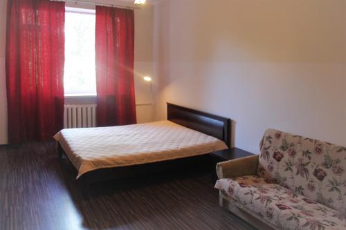 a bedroom with a bed and a couch and a window at Apartments on Tsentralnaya Ploshad in Kaliningrad