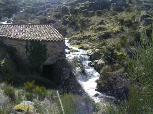 a river with a building in the middle of a mountain at Posada Real La Mula de los Arribes in Villardiegua de la Ribera
