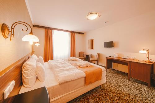 ヘーヴィーズにあるPark Hotel Hévízのベッドとデスクが備わるホテルルームです。
