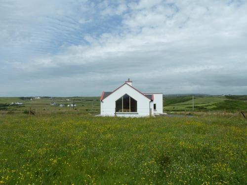a small white house in a field of grass at Mary's Meadow in Doolin