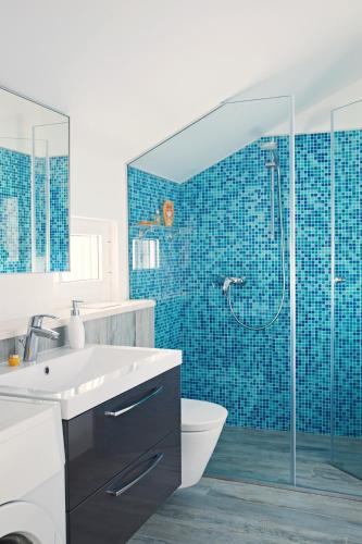 a bathroom with a toilet and a shower with blue tiles at Holiday House KALIMERO in Primošten