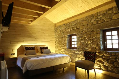 a bedroom with a bed and a stone wall at Le Vieux Logis in Yvoire